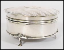 A silver hallmarked ladies dressing table pill pot  being raised on hoof feet  with engine turned