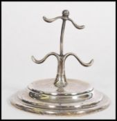 A silver hallmarked ring stand tree with 4 wavey arms over terraced base being hallmarked for