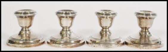 A set of 4 silver hallmarked stub candlesticks with reeded terraced bases and single sconces.