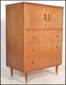 A mid century Danish inspired  tallboy pedestal chest of drawers having linen cupboard over bank