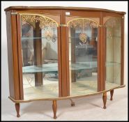 A  mid century retro display cabinet in faux wood being raised on turned legs with sliding glass