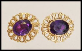 A pair of 20th century gold yellow metal earrings with inset amethysts and decorative settings.