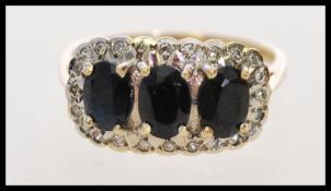 A hallmarked 9ct gold ring with three oval cut blue sapphires (approx 6mm x 4mm) surrounded with