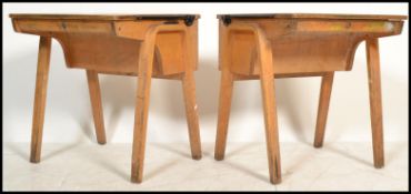 A pair of mid 20th Century school / students desks, lift up top with storage below raised on bent