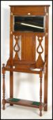 A 1920's Art Nouveau gold oak hallstand with central glove drawer having mirror upright with coat