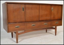 A 1960's / mid century Gomme / G-Plan teak wood cross over sideboard credenza being raised on