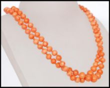 A early 20th century necklace with coral beads and a decorative carved floral detail clasp.