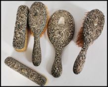 A collection of silver white metal vanity items, including clothes brushes, hair brushes and hand