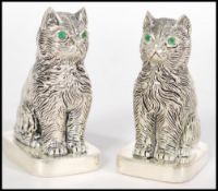 A pair of stamped 800 silver condiments in the form of cats having inset green stone eyes. Weight