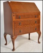 A 1920's mahogany Queen Anne revival bureau desk being raised on cabriole legs with a bank of