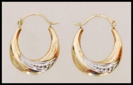 A pair of 9ct gold hooped earrings with silver detailing weighing 1g. Measures 2 cm high.