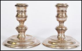 A pair of silver hallmarked candlesticks raised on filled stepped circular bases with knopped stems.