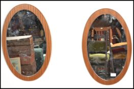 A pair of vintage retro mid 20th century teak wood frameless mirrors of oval form having central