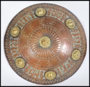 A 20th century decorative domed metal shield having embossed and engraved detailing to the rim and
