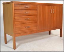 A mid century teak wood sideboard credenza being raised on squared legs with a bank of 4 drawers