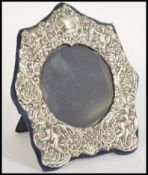 A hallmarked 20th century silver picture frame having a scrolled design with cherub puttis and easel