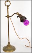 A vintage brass gas lamp converted into an anglepoise lamp with a roped wire, on a circular pedestal