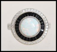 A stamped 925 silver metal halo ring in the Art Deco style set with white and blue stones around a