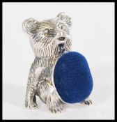 A silver teddy bear pin cushion with a with a blue fabric panel. Weight 14g. Height approx 2.5 cm.