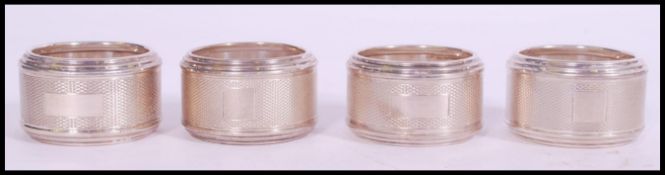 A set of four silver hallmarked engine turned napkin rings, makers marks for Sanders & Mackenzie,
