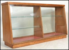 A vintage mid 20th Century oak tapering shop display cabinet, glazed front with two tiers of shelves