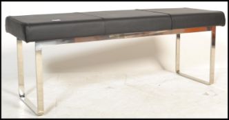 A contemporary Barcelona style bench with black leather cushion, raised on chrome supports. Measures
