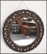 An early 20th century carved oak decorative circular wall mirror having oak pierced foliate design