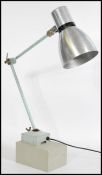 A vintage retro 20th century industrial work desk lamp raised on a wooden base with square metal