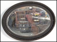 A 19th century oval bevelled glass mirror, in a painted carved oak frame. Measures: 65cm high x 90cm