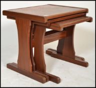 A retro 20th Century G PLan teak nest of three graduating tables, with inset hammered copper tops,