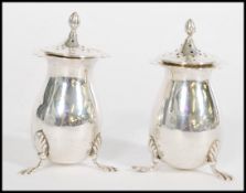 A pair of early 20th century Edwardian silver hallmarked pepperettes raised on acanthus tripod
