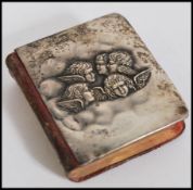 An Edwardian silver hallmarked common book of prayers, cast in relief with winged putti to the