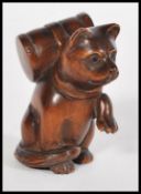 A 20th century Japanese wooden netsuke in the form of a cat sat on it's hind legs with it's front