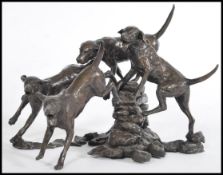 A bronze sculpture of a group of hunting hounds jumping over a wall by Michael Simpson, baring the