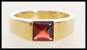 A 20th century stamped 750 gold ring with inset red stone weighing 4.5g size O.
