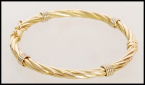 A hallmarked 9ct gold bangle of twisted form with a hinge opening. Weight 8.3g. Measures 8 cm