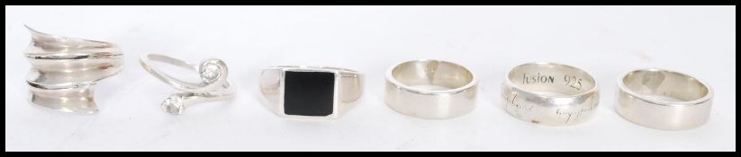A selection of silver rings to include a signet ring with a black stone and a lord of the rings
