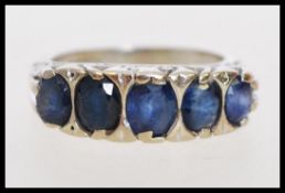 An 18ct white gold blue stone ring having five large graduating faceted blue stones with scrolled