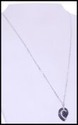A hallmarked 9ct white gold pendant necklace with a leaf form pendant having inlaid black and