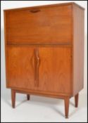 A retro vintage teak wood cocktail cabinet. The cabinet having a metamorphic action drop down top