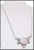 A stamped 925 silver necklace with a rose quartz pendant with decorative floral surround. Weight