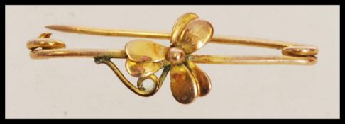 A yellow metal brooch pin with a central flower decoration weighing 1.1g.