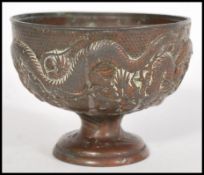 A bronze Chinese water bowl with embossed decoration to the sides depicting Chinese dragons,