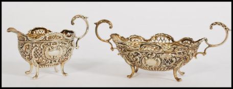 A silver hallmarked twin scroll handled rococo and fret pierced sugar bowl raised on scroll feet