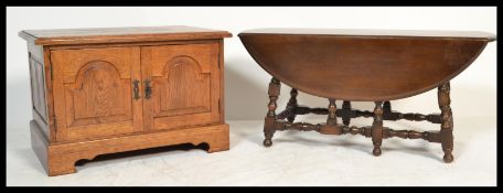 An Ercol 20th century dark beech and elm wood drop leaf coffee table being raised on bobbin turned