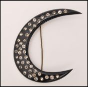 A 1920s large black celluloid brooch pin in the form of a crescent moon set with paste. Measures 3