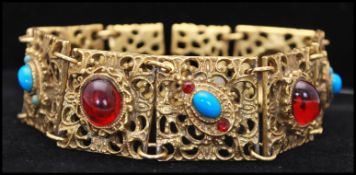 A 1950s gold tone Etruscan revival bracelet set with blue and white cabochons having a clip clasp.