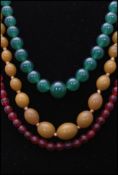 A collection of three vintage necklaces to include a jade glass, opera cherry glass and amber