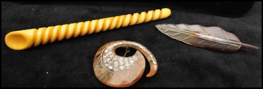 A early 20th century carved horn brooch in the shape of a leaf, together with a large bakelite
