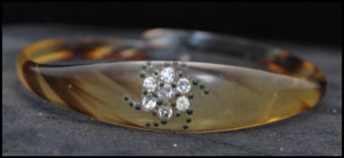 A Victorian carved horn bangle bracelet with paste set motif. Measures 3 inches diameter.